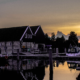 Boten aangemeerd in een jachthaven bij zonsondergang, met een traditioneel gebouw op de achtergrond.