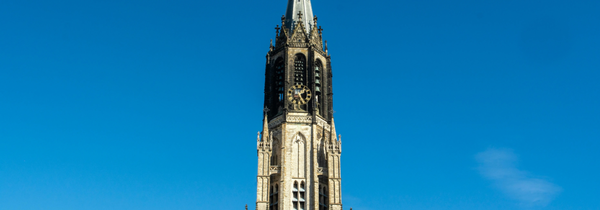 Middeleeuwse kerktoren in Amersfoort tegen een heldere blauwe lucht.