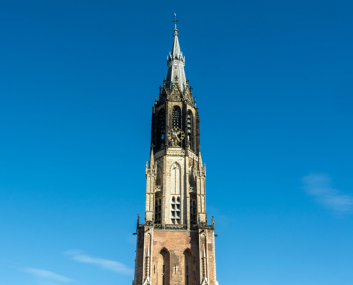 Middeleeuwse kerktoren in Amersfoort tegen een heldere blauwe lucht.