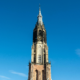 Middeleeuwse kerktoren in Amersfoort tegen een heldere blauwe lucht.