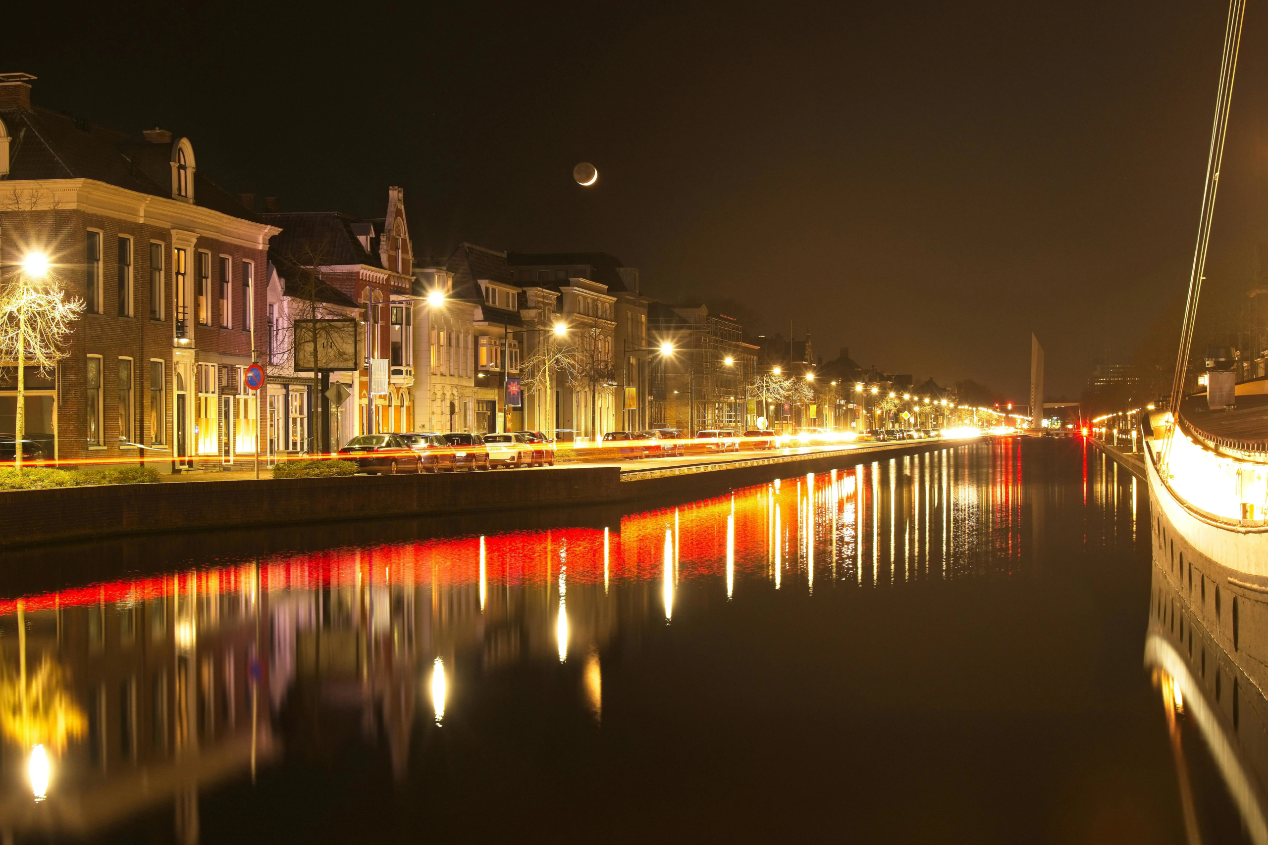 Verlichte grachtenpanden en reflecties in het water tijdens een heldere nacht in Leeuwarden.