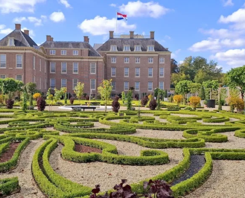 Barokke tuin met symmetrische hagen voor Paleis Het Loo in Apeldoorn, met Nederlandse vlag op het dak.
